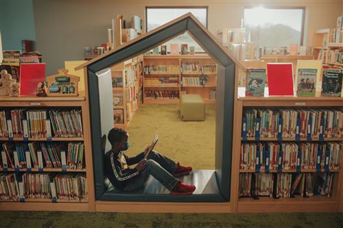 Student reads a book in a cubby.