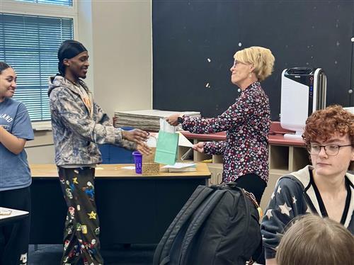woman handing a gift bag to a student