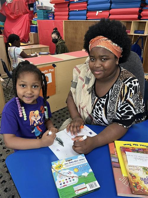 A middle school student and a Wasena student color together at a table.