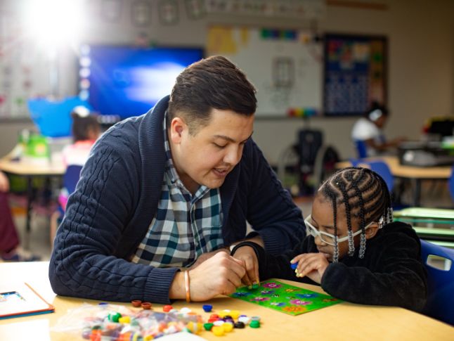 Teacher working with a student at a table.