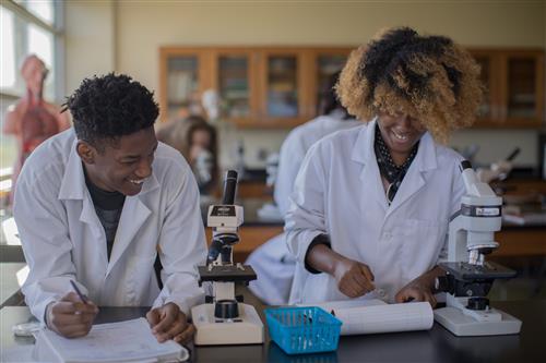 Students working in science class over a microscope.