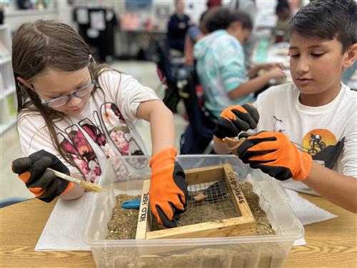 Students dig through a box on an archaeology dig.